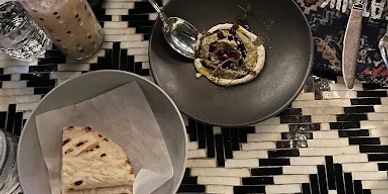 Table with quesadilla, dessert, and drinks on a patterned tablecloth.