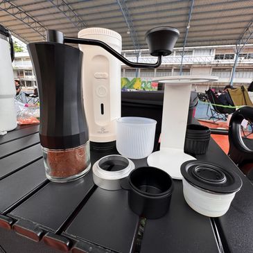 Coffee grinding setup with hand grinder and coffee accessories.