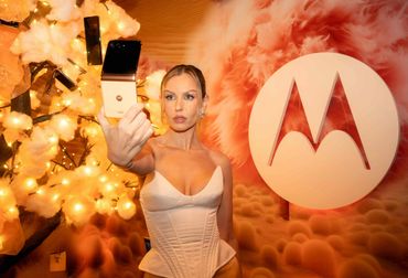 Woman posing with a Motorola phone at a festive event.