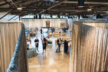 People browsing booths at a spacious indoor market or event.