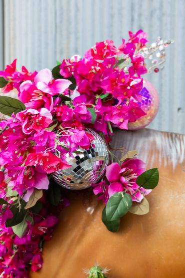 Bright pink flowers with disco balls on a brown surface.