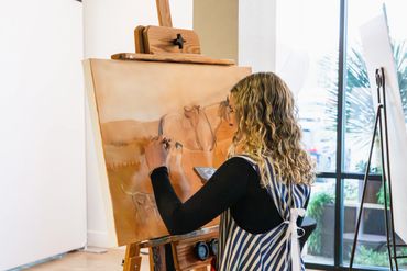 A woman painting a horse portrait on a canvas indoors.
