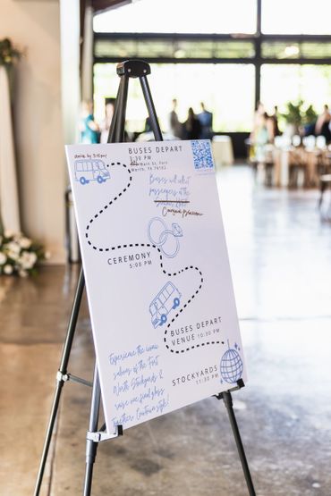 Wedding schedule sign on an easel with bus departure times and ceremony details.