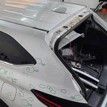 Damaged white car with marked dents and scratches.