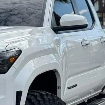 Close-up of a white Toyota Tacoma truck's front side.