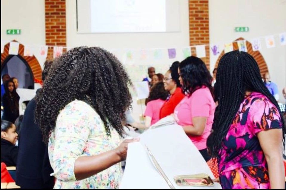 Women engaging in a lively community event indoors with colorful decorations.