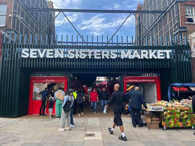 The entrance of Seven Sisters Market with people walking and shopping.