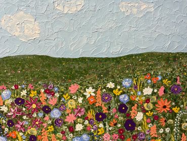 Colorful flowers in a textured field beneath a cloudy sky.