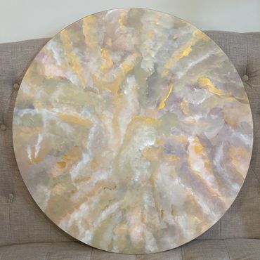 Abstract circular artwork with soft gold, silver, and cream tones.