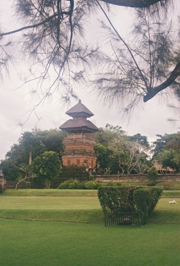 Traditional tower amidst greenery with trees in the foreground.