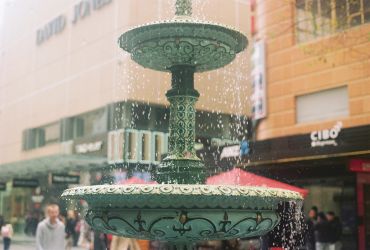 Decorative green fountain in a busy urban area.