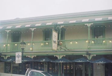 Historic two-story building with a green facade and balcony.