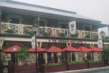 The German Arms Hotel exterior with red umbrellas.