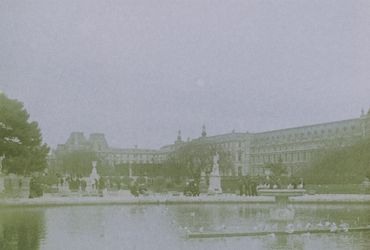 People enjoying a park with historic buildings in the background.