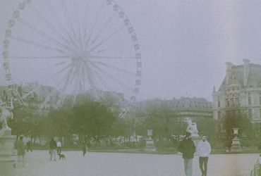 A foggy day at a park with a large Ferris wheel and people walking.
