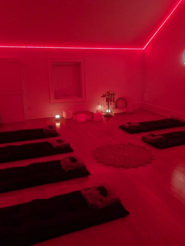 Dimly lit room with red lighting and arranged mats.