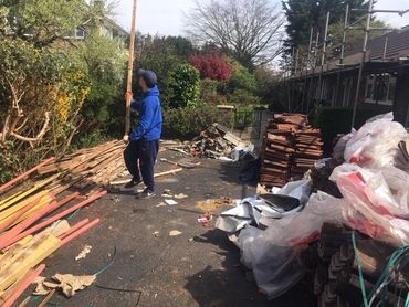 Worker in action, rubbish clearance of old roof tiles, batten and roof underlay.