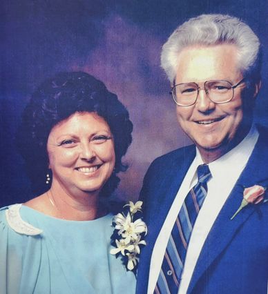 Smiling elderly couple dressed formally with floral corsages.