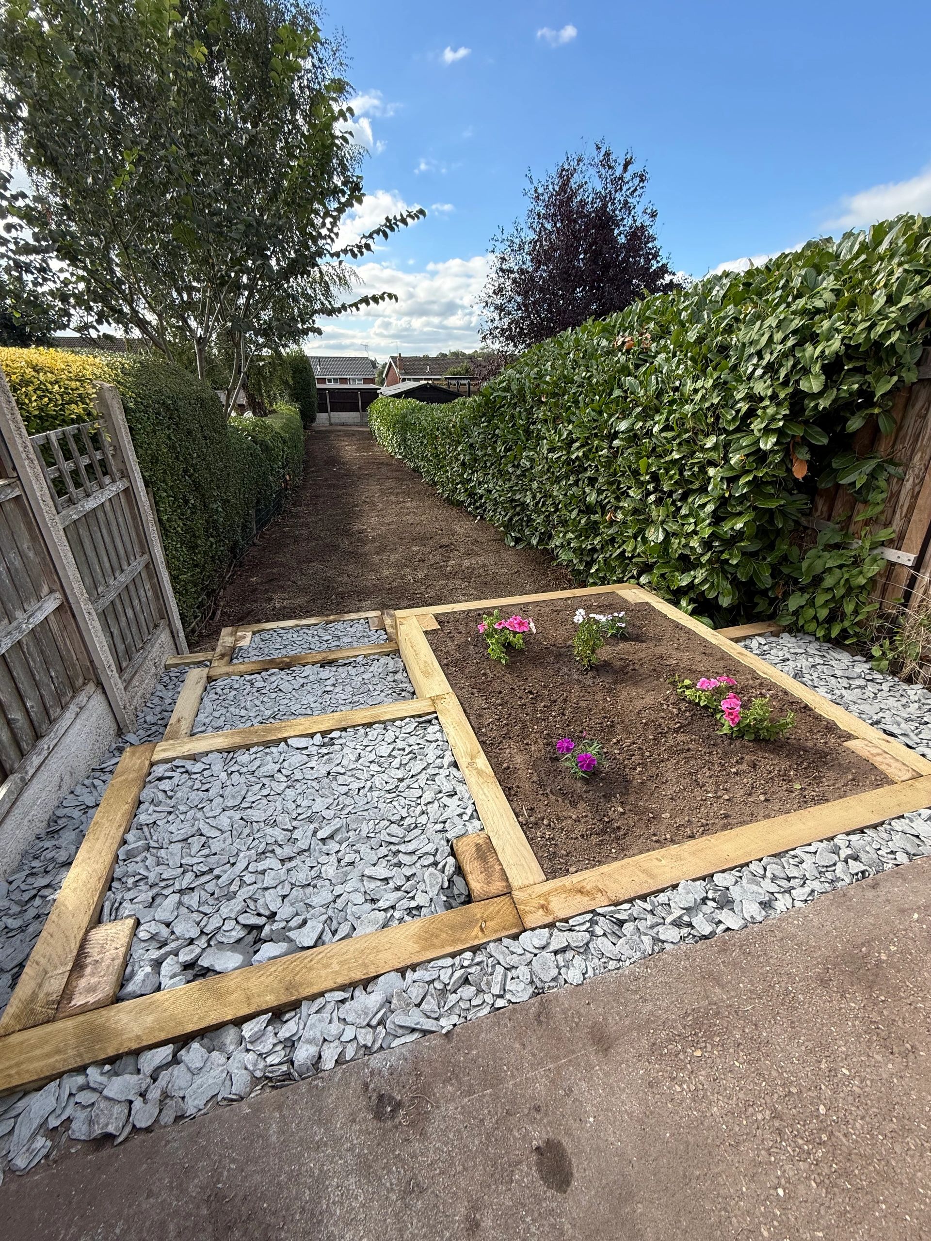A neat garden pathway with timber sleeper steps and raised bed with flowers.