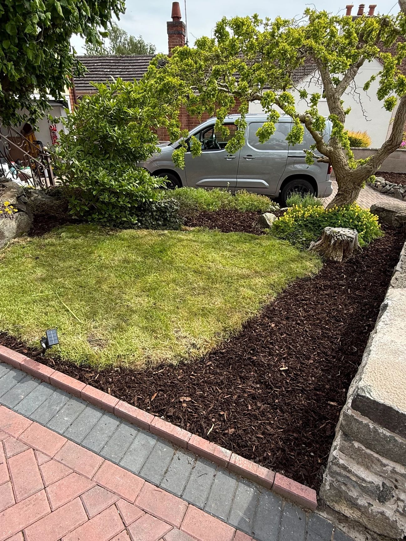 Well-maintained garden with lawn, shrubs, and new mulch installed.