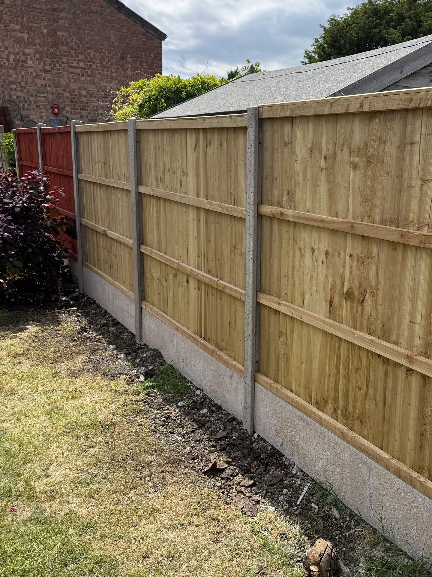 Newly installed concrete and timber fencing in a garden.