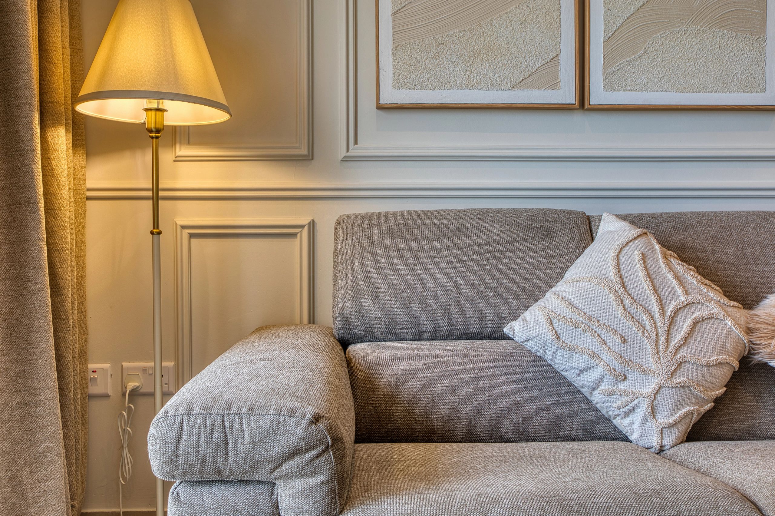 Cozy gray sofa with a textured white pillow and warm lamp lighting in an elegant living room.