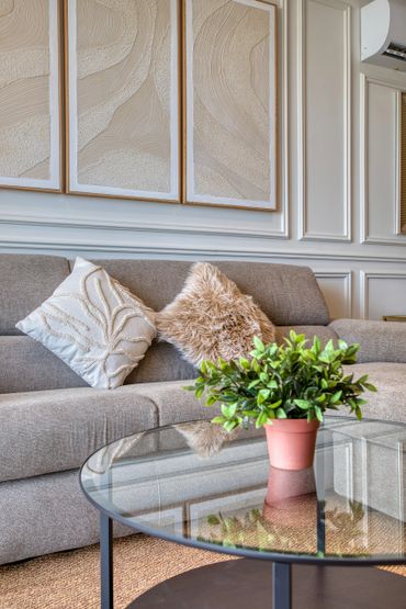 Cozy living room with textured pillows and a glass coffee table.