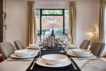 Elegant dining table set with white plates and wine glasses in a cozy room.