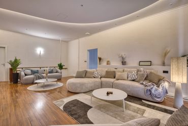 Modern living room with curved sofas and warm lighting.