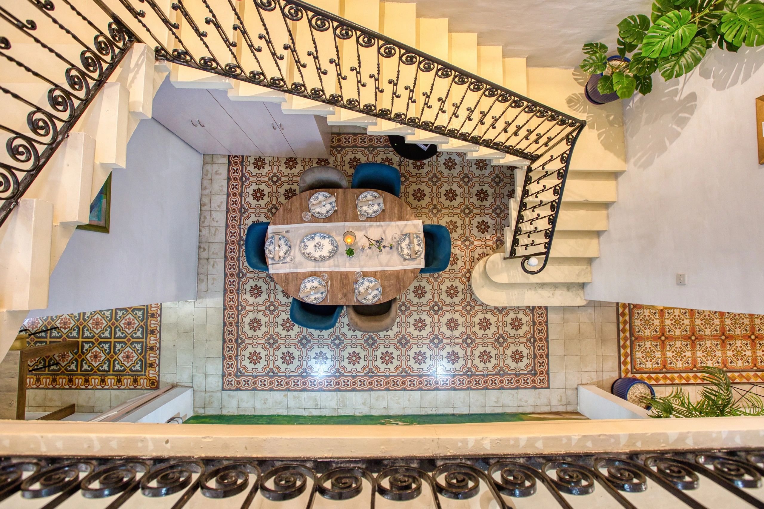 Elegant dining area viewed from staircase with patterned tiles and blue chairs.