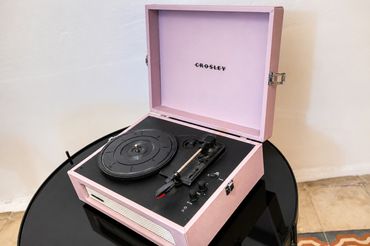 Pink Crosley record player on a black round table.
