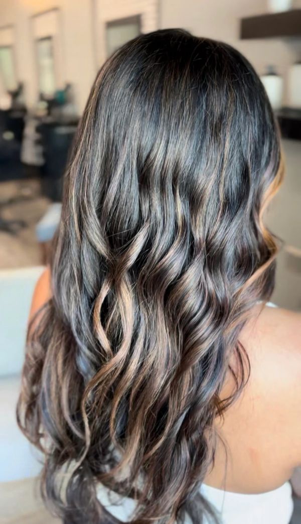Long wavy hair with subtle blonde highlights.
