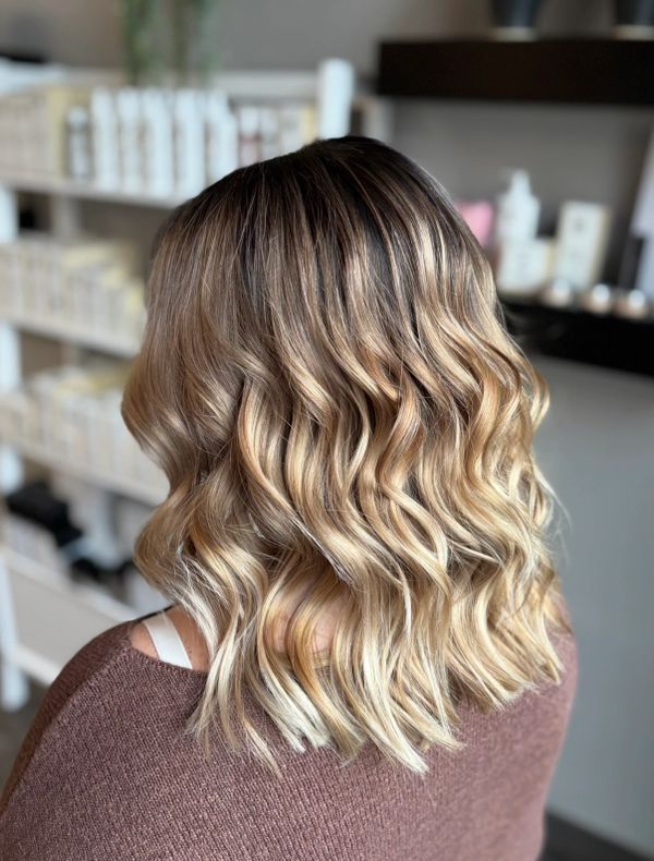 Wavy blonde balayage hairstyle on medium-length hair.