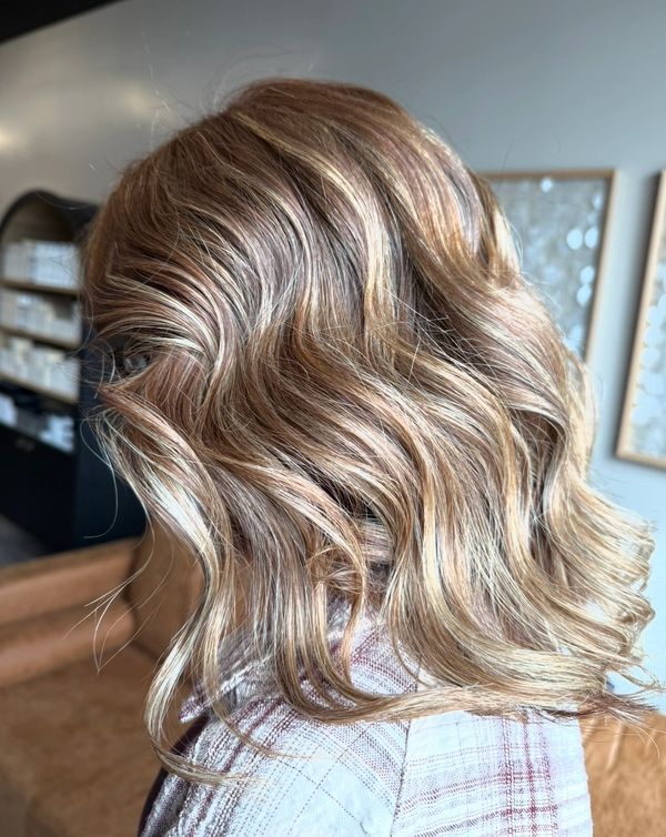 Soft, wavy blonde hair with subtle highlights styled elegantly.