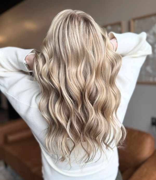 Long, wavy blonde hair with highlights styled beautifully.