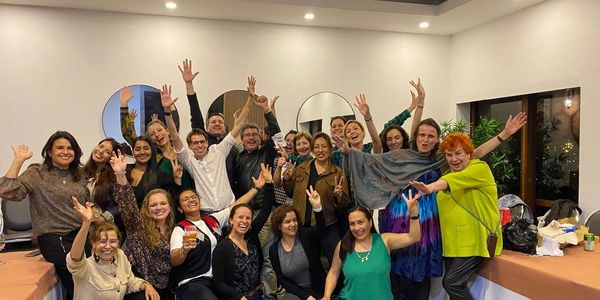 Group of joyful people raising hands and smiling indoors.