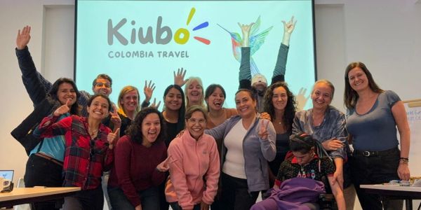 A joyful group posing under a Colombia travel logo, celebrating.