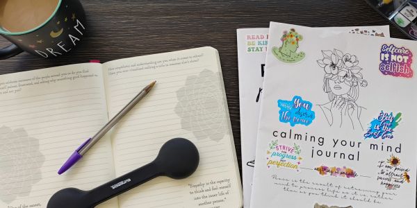 Journals, pen, and coffee on a wooden desk.