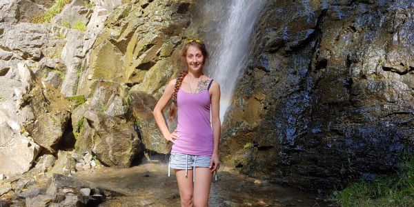 Woman standing in front of a waterfall.
