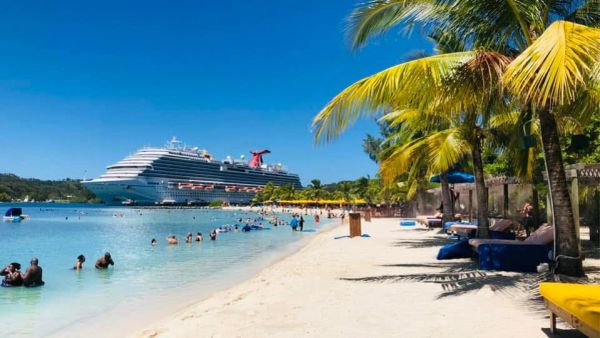 Beach scene with cruise ship and palm trees.