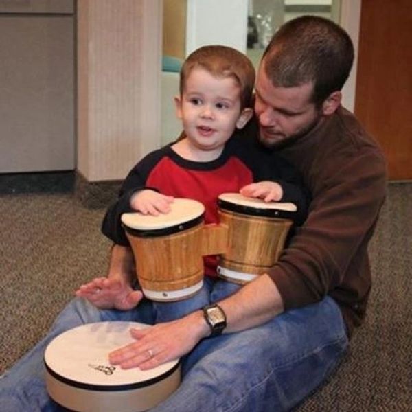 A man and a child playing drums together indoors.