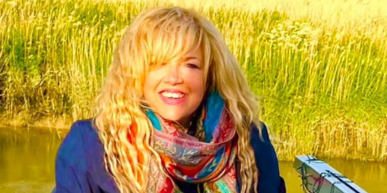Smiling woman with blonde hair near a body of water.