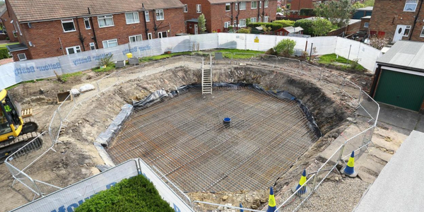 Excavation site for a large circular foundation in a residential area.