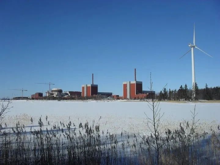 Nuclear power plant with a nearby wind turbine on a clear winter day.