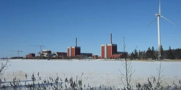 Nuclear power plant with a nearby wind turbine on a clear winter day.
