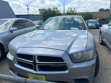 Silver Dodge Charger parked in a lot on a cloudy day.