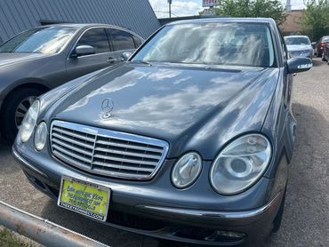 A grey Mercedes-Benz parked outdoors with a yellow dealership plate.