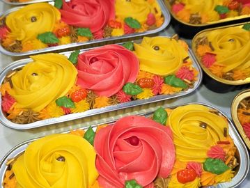 Colorful flower-themed cakes with vibrant frosting and autumn decorations.