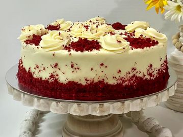 A red velvet cake with cream cheese frosting on a decorative stand.