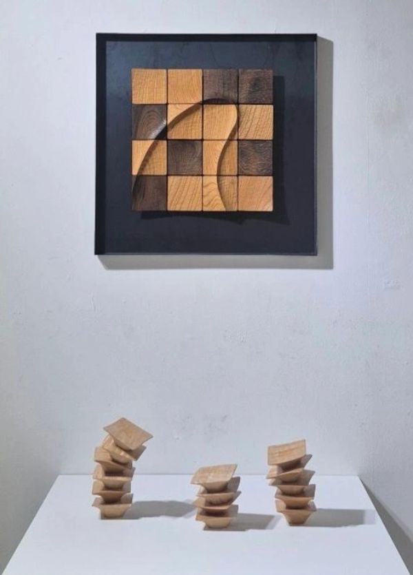Wooden geometric art pieces displayed on a white surface and mounted on a wall.